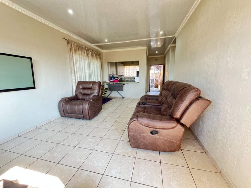 Open-plan living area featuring tiled flooring, recessed lighting, and a convenient pass-through window connecting to the kitchen space.