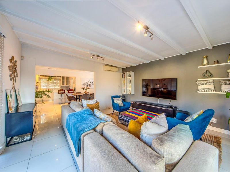 Spacious open-plan living area featuring tiled floors, exposed beam ceilings, and integrated air conditioning, flowing seamlessly into the adjacent kitchen and dining space.