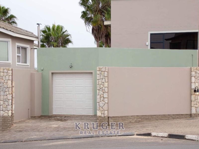 Front view of the property featuring a secure garage, stone-clad pillars, and a paved driveway entrance.