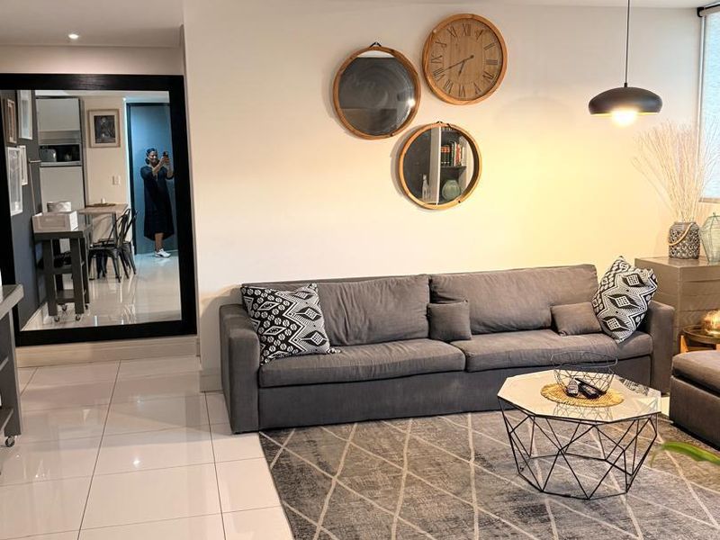 A modern living room featuring polished porcelain floor tiles, recessed downlighting, and a contemporary pendant light fixture.