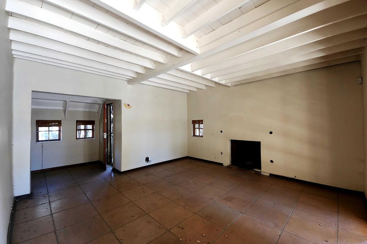 Spacious living area featuring exposed white timber beam ceilings, terracotta floor tiles, and a built-in fireplace.
