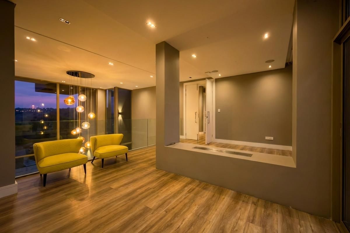Modern living area featuring wood-look flooring, recessed ceiling lighting, a built-in fireplace, and floor-to-ceiling glass windows with expansive views.