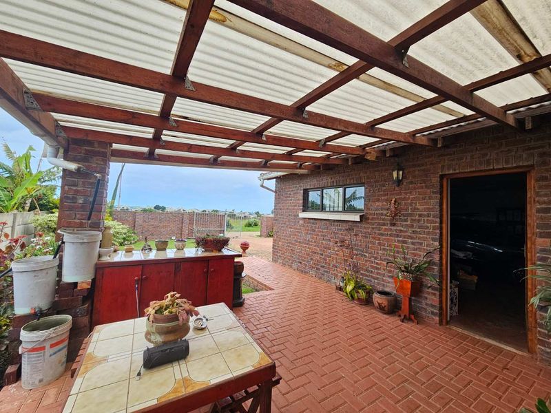 Covered outdoor patio area featuring a timber pergola with corrugated roofing, brick paving, and direct access to the home's exterior.