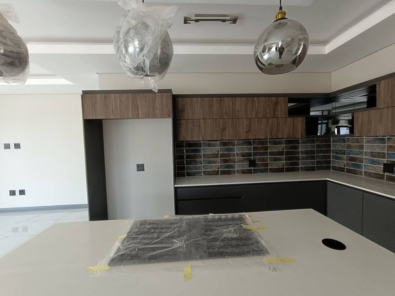 Modern kitchen featuring dark wood and matte cabinetry, stone countertops, and a stylish subway tile backsplash in a newly finished space.