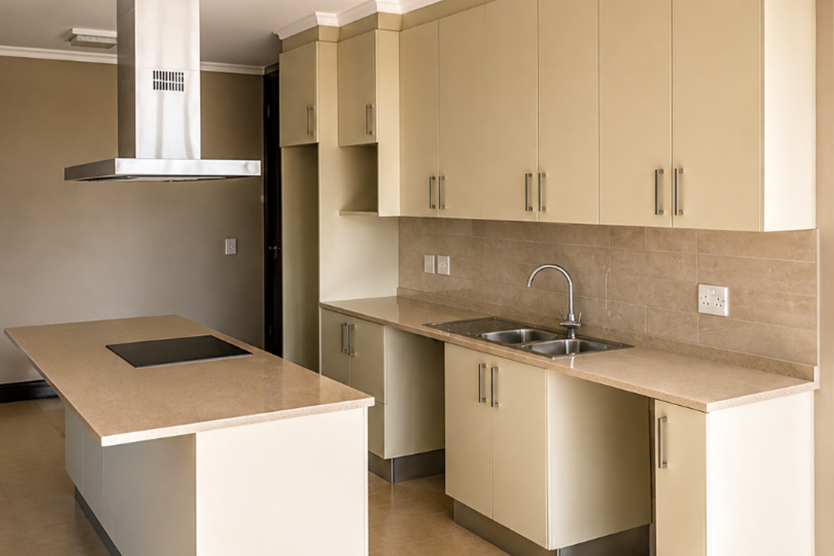 A modern, empty kitchen featuring light-toned cabinetry, stone countertops, a central island with a built-in hob, and a stainless steel extractor fan.