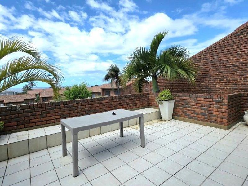 An open-air balcony featuring tiled flooring and a brick perimeter wall, offering an elevated outdoor space with neighbourhood views.