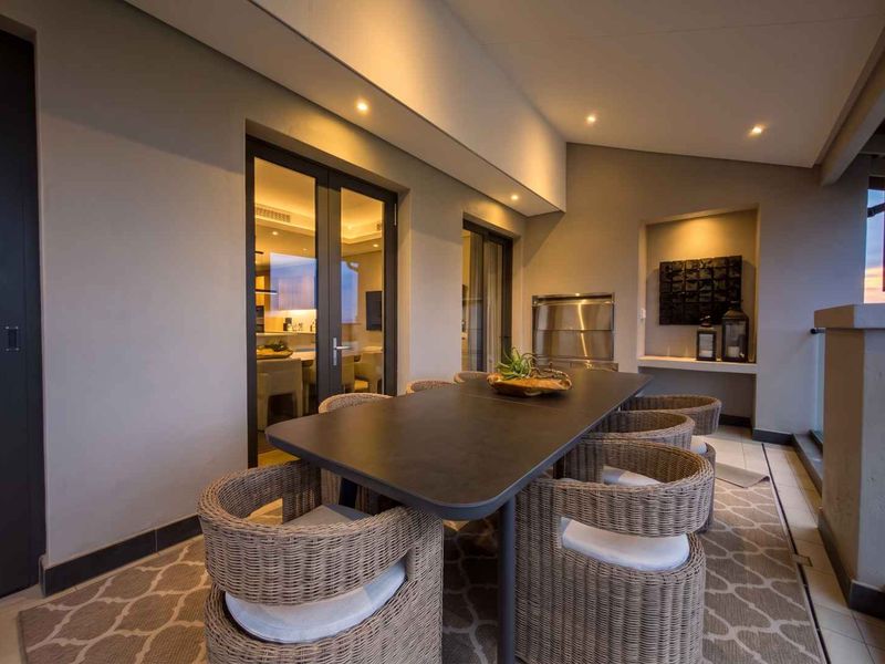 Covered balcony featuring a built-in braai, recessed lighting, and direct access to the interior living space through glass doors.