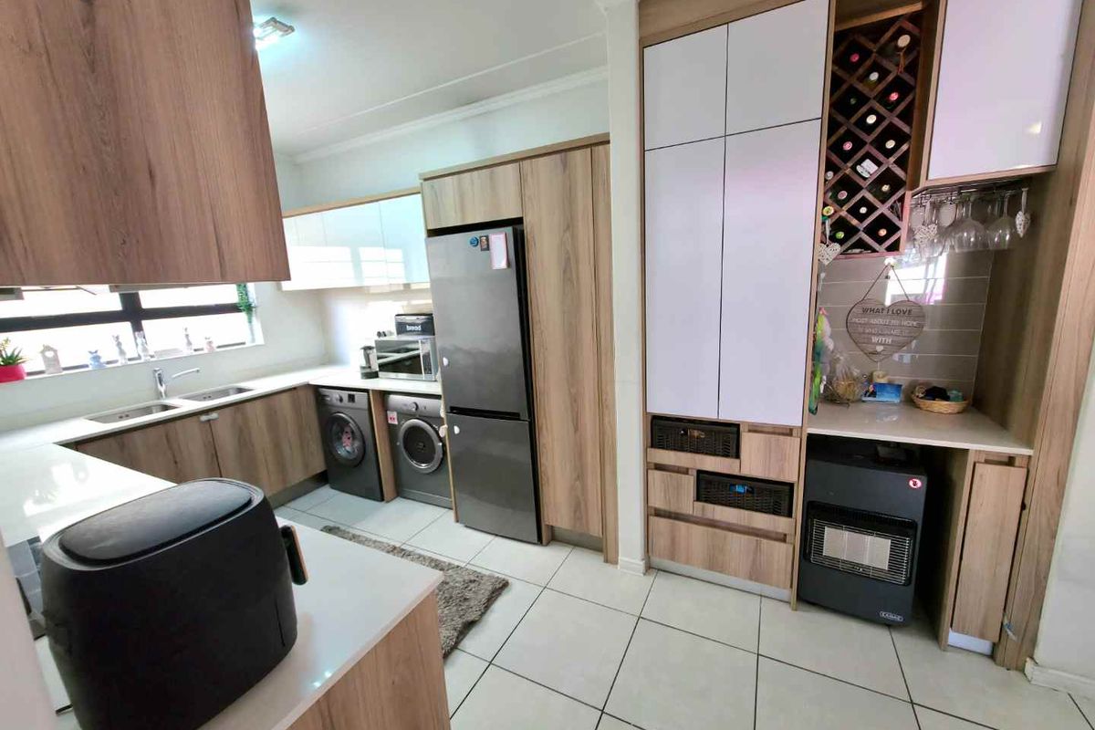 Modern kitchen featuring wood-grain cabinetry, integrated wine rack, tiled flooring, and built-in appliance spaces for a sleek, functional layout.