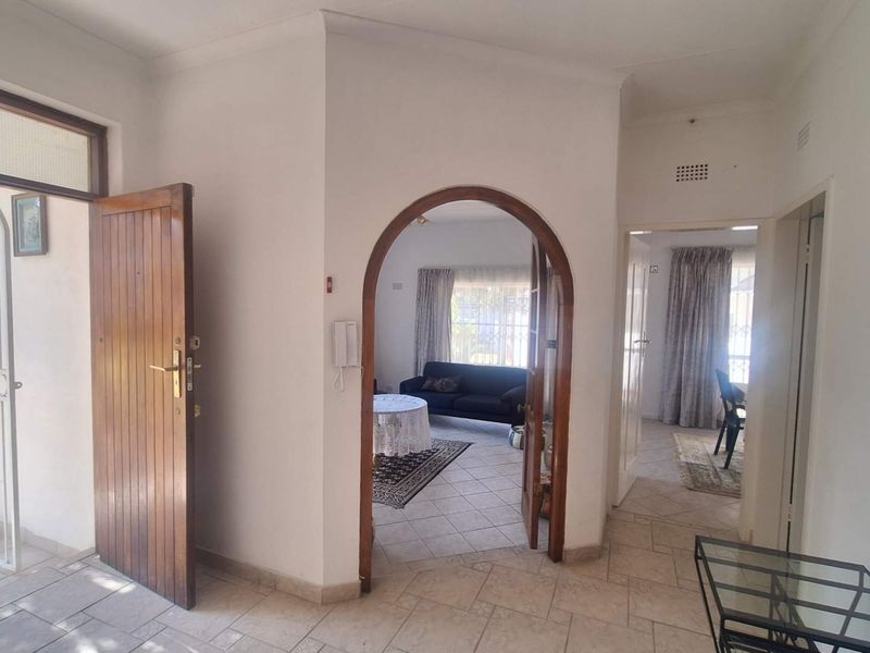 Entrance hall featuring tiled flooring, an arched doorway leading to the living area, and a secure timber front door with an integrated security gate.