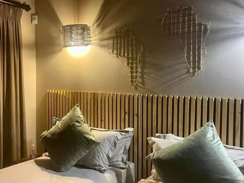A cozy bedroom featuring a rustic thatched roof with exposed timber rafters and a modern slatted timber headboard.