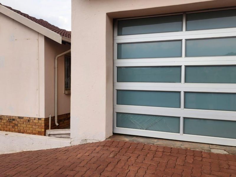 Front exterior view showing a modern sectional garage door with frosted glass panels and a paved driveway.