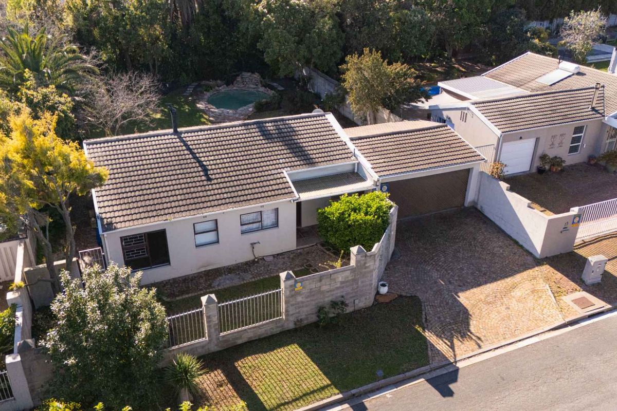Aerial view of a residential property featuring a tiled roof house, paved driveway, attached garage, and a private swimming pool in the rear garden.