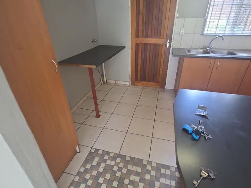 A functional kitchen area featuring tiled flooring, built-in cabinetry, a double sink, and a dedicated prep counter space.