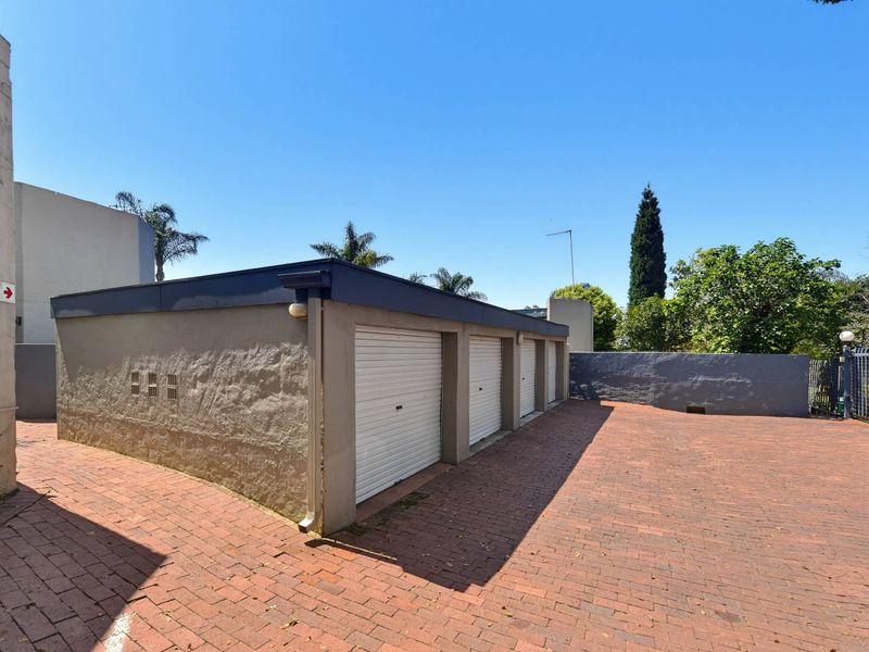 A well-maintained triple garage block featuring roller shutter doors and a brick-paved driveway area.