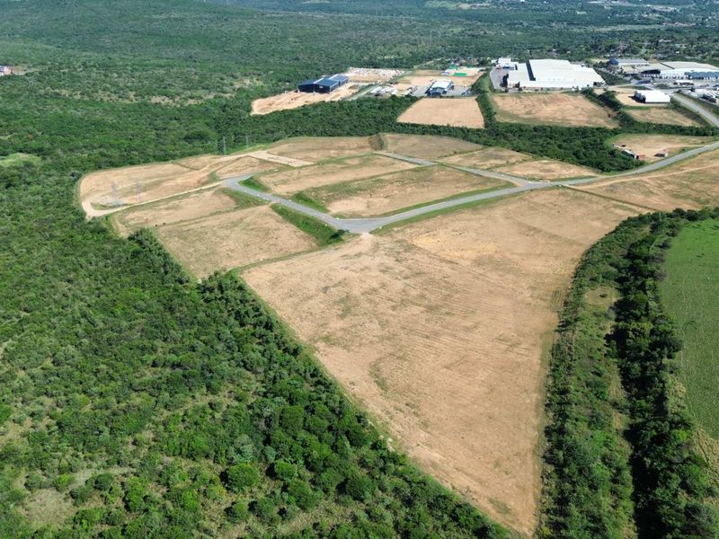 Aerial view of a large, cleared industrial land parcel featuring established access roads and surrounding natural vegetation.