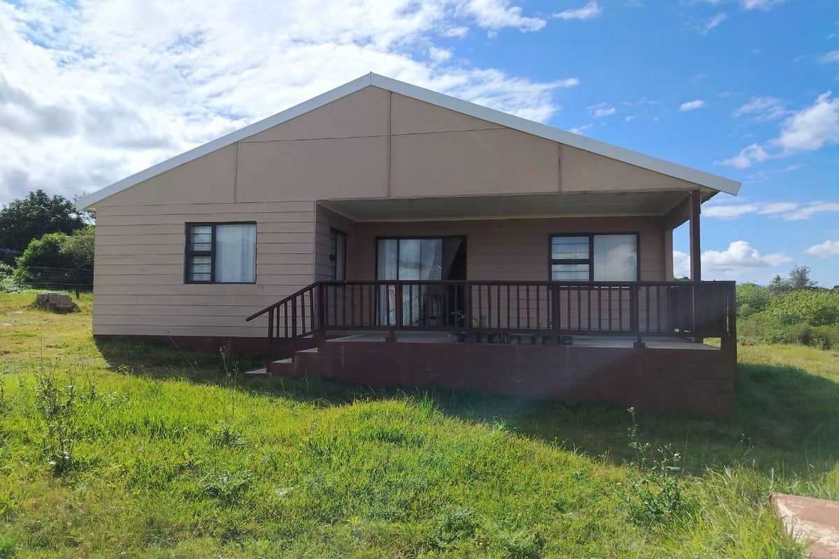Rear view of a detached house featuring a timber deck, sliding glass doors, and aluminium window frames set within a large grassy yard.