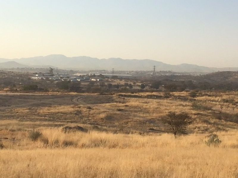 A wide-angle view of the expansive, undeveloped commercial land featuring natural dry grass terrain and distant mountain vistas.