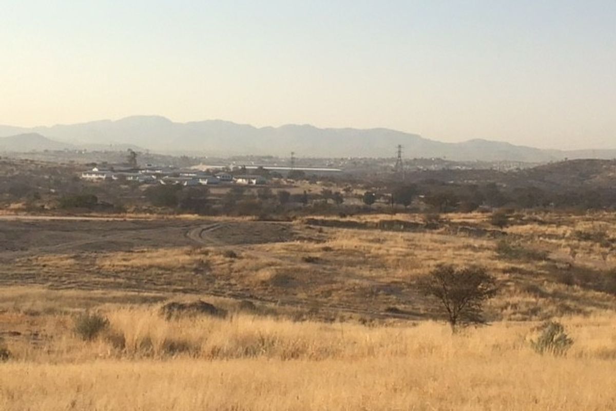 A wide-angle view of the expansive, undeveloped commercial land featuring natural dry grass terrain and distant mountain vistas.