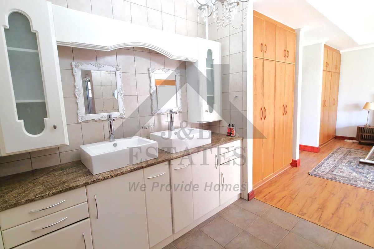 A spacious bathroom featuring a double vanity with vessel sinks, granite countertops, and extensive built-in cabinetry for storage.