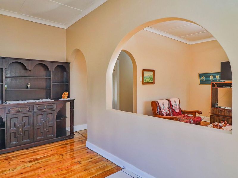 A living area featuring polished hardwood flooring and a distinctive architectural archway connecting to an adjacent space.