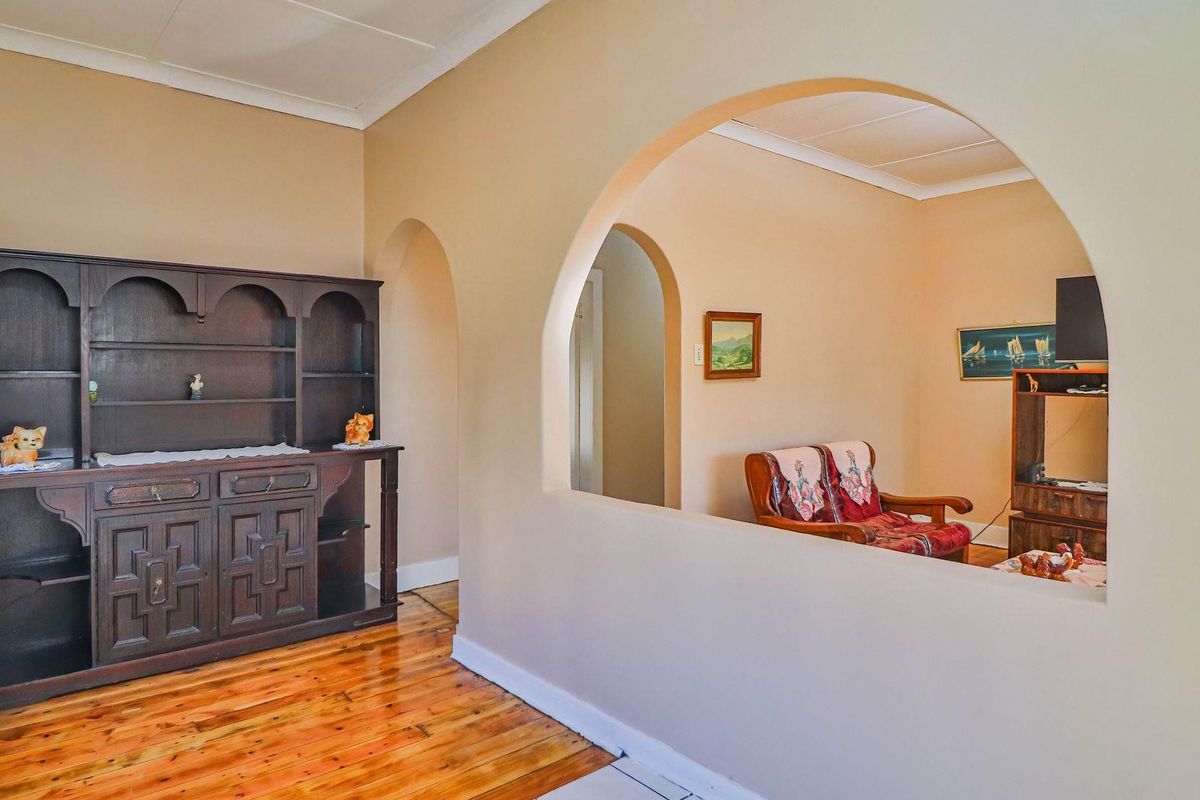A living area featuring polished hardwood flooring and a distinctive architectural archway connecting to an adjacent space.