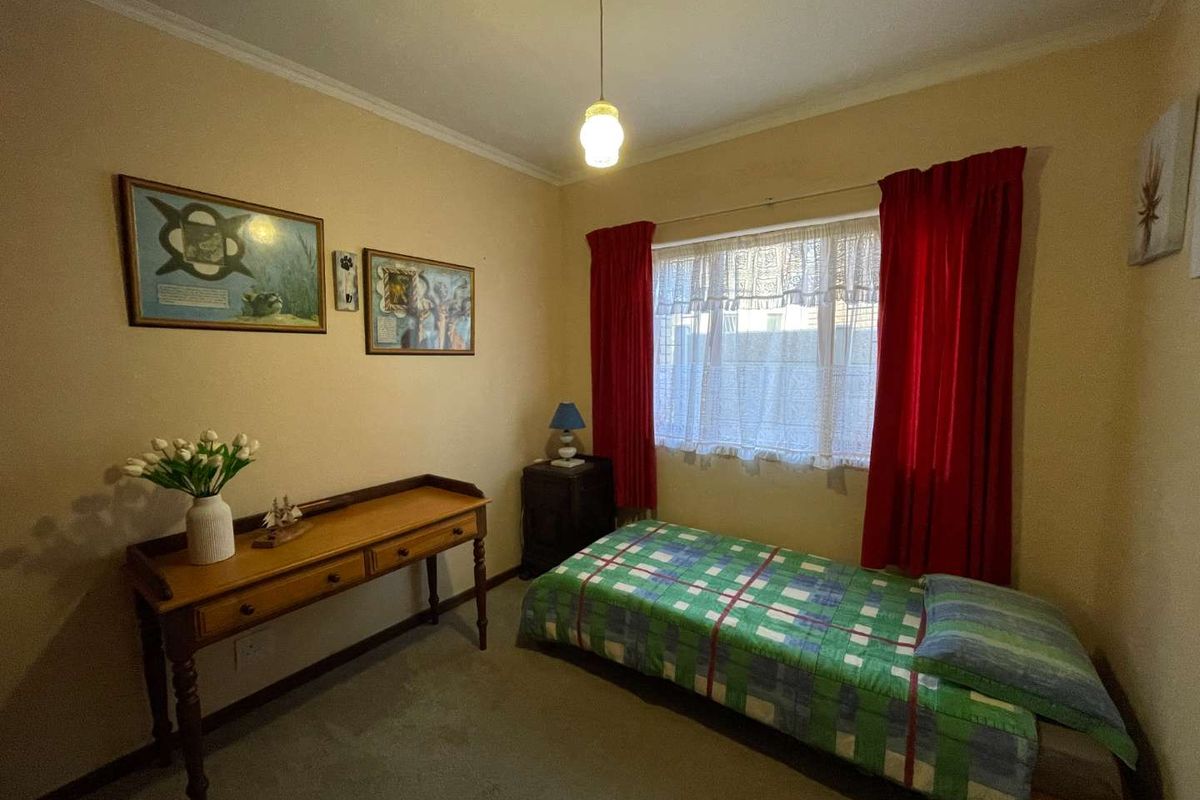 A standard bedroom featuring neutral wall finishes, carpeted flooring, and a window with fitted curtain tracks.
