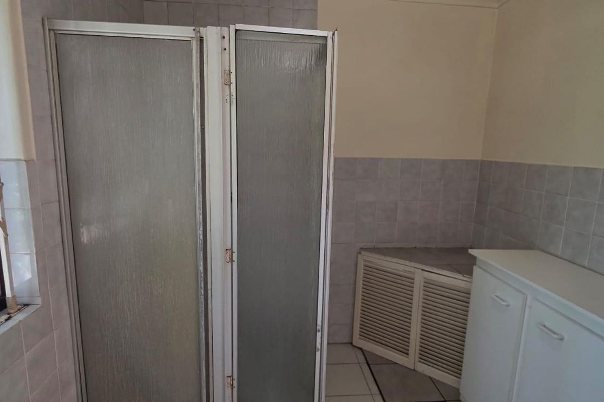 A dated bathroom featuring a shower enclosure, tiled finishes, and built-in vanity cabinetry, offering potential for a modern renovation.