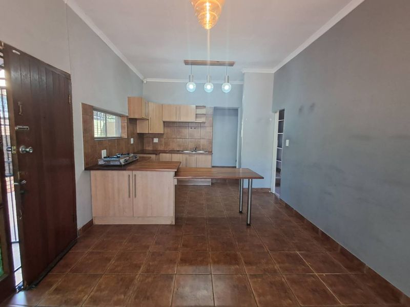 Open plan kitchen area featuring built-in cabinetry, laminate countertops, a breakfast bar, and ceramic tile flooring in a neutral, functional layout.