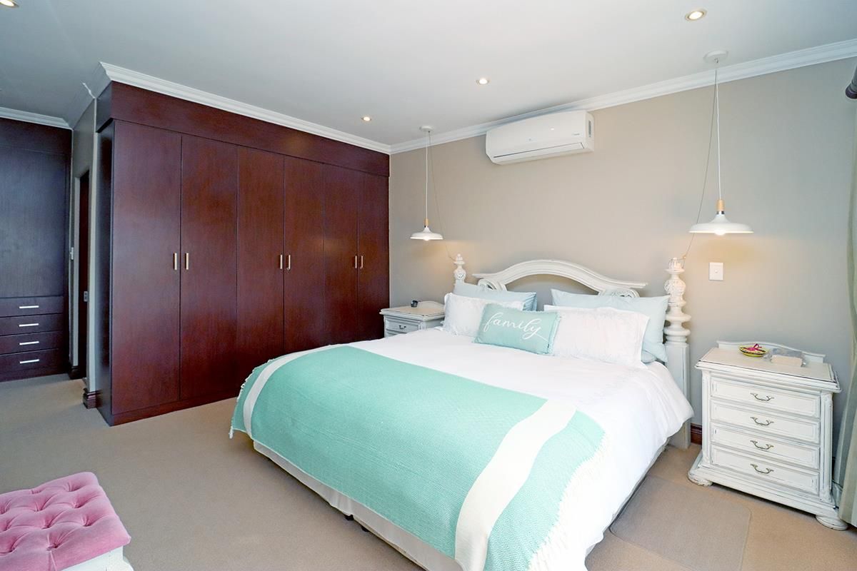 A well-maintained bedroom featuring extensive dark wood built-in cabinetry, neutral wall tones, recessed lighting, and a wall-mounted air conditioning unit.