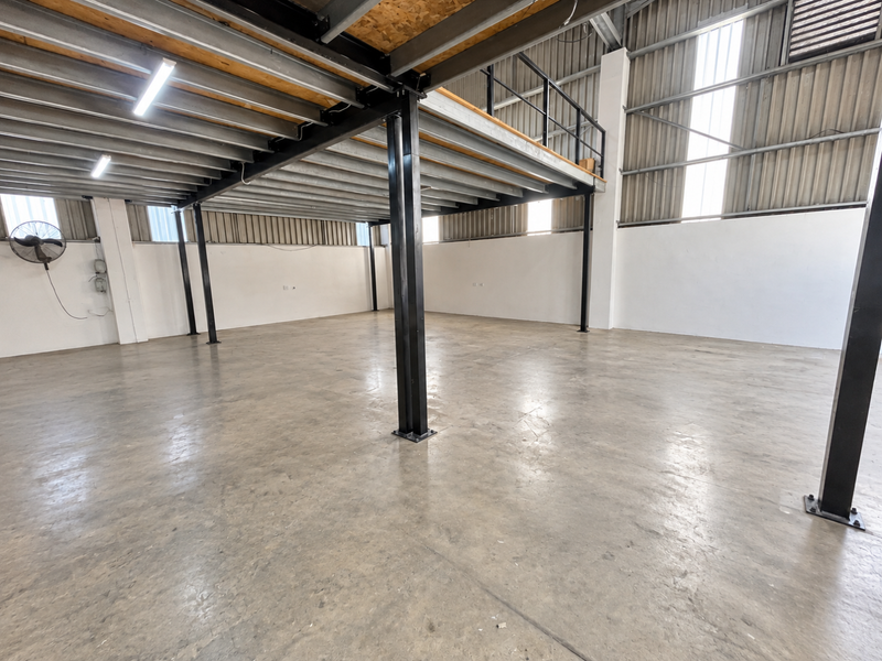 Spacious industrial utility area featuring a steel mezzanine level, polished concrete flooring, and high ceilings with exposed structural steel elements.