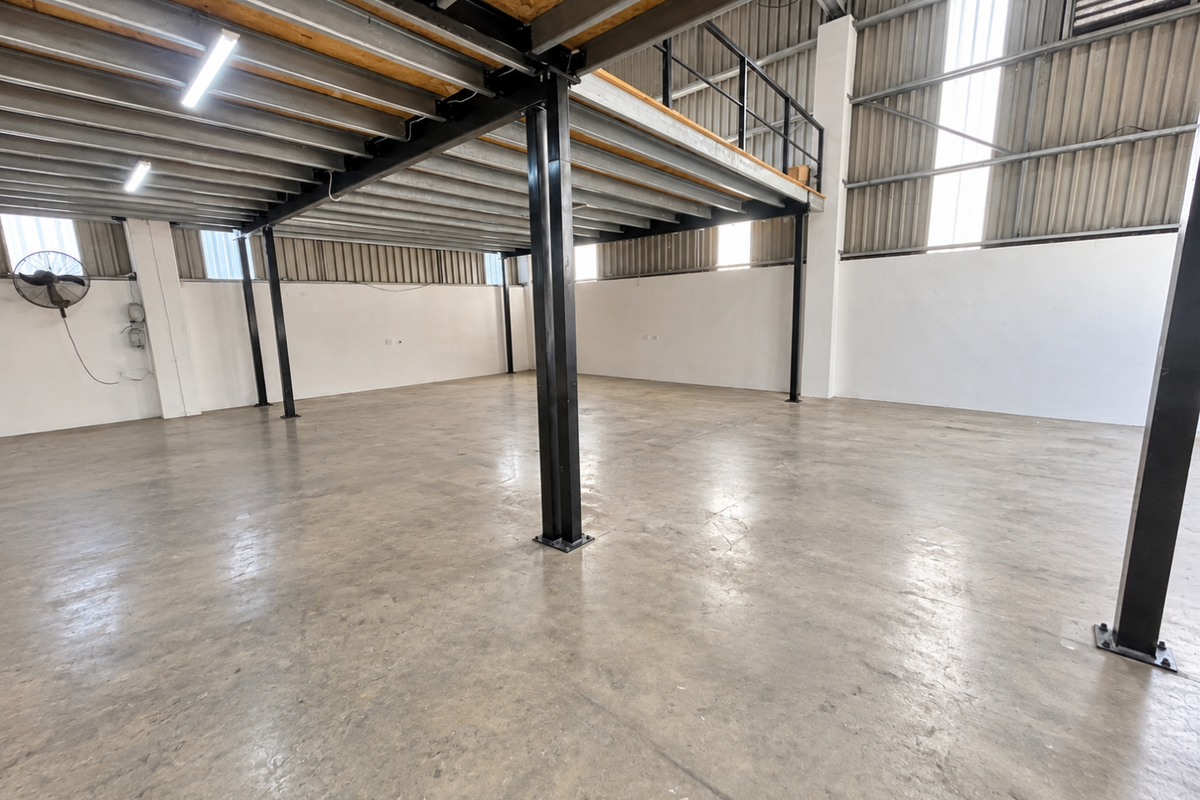 Spacious industrial utility area featuring a steel mezzanine level, polished concrete flooring, and high ceilings with exposed structural steel elements.