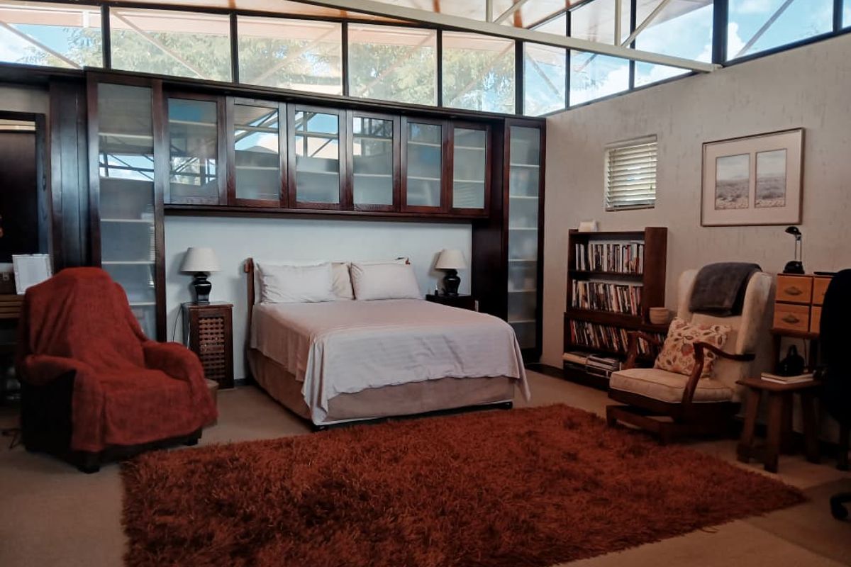 Spacious bedroom featuring extensive built-in dark wood cabinetry, high clerestory windows providing ample natural light, and neutral carpeting.
