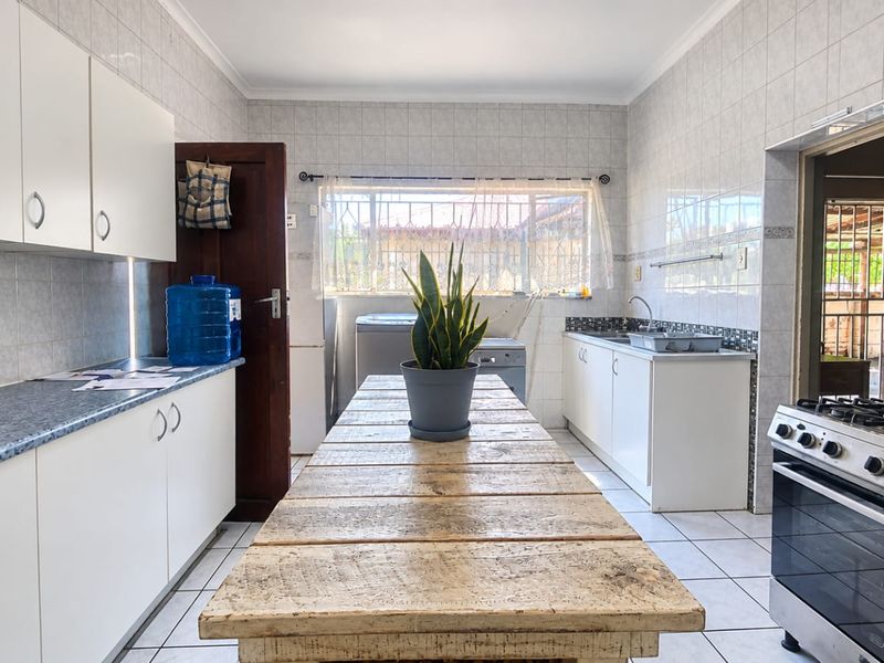 A functional kitchen featuring white cabinetry, tiled walls, a gas stove, and a central workspace, offering a practical layout for daily meal preparation.