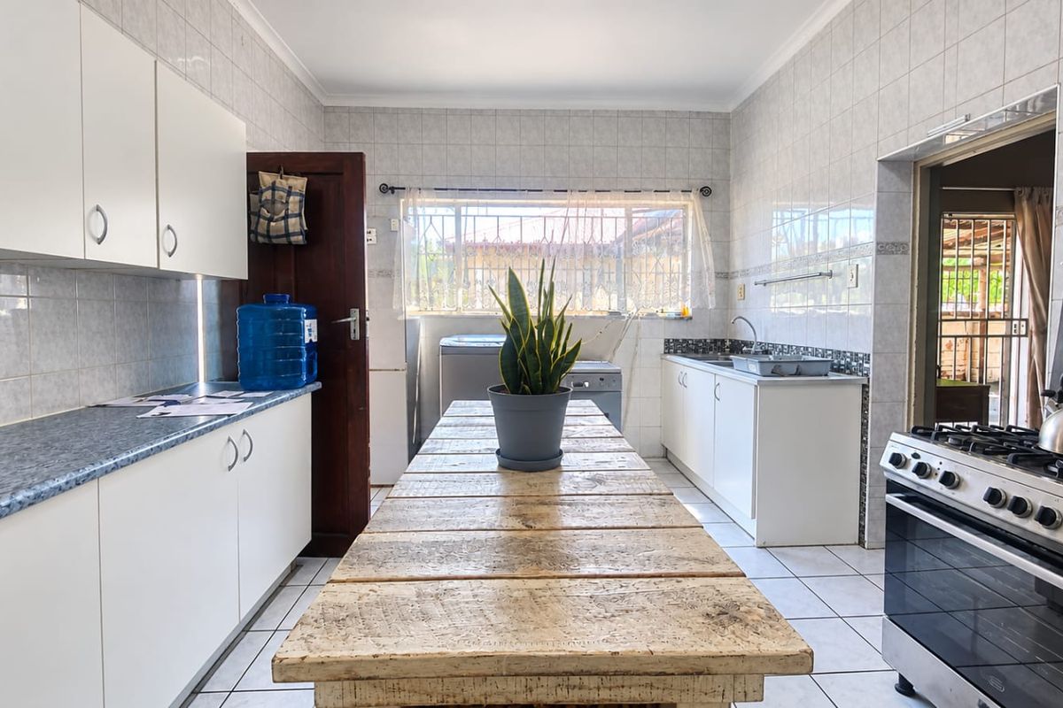 A functional kitchen featuring white cabinetry, tiled walls, a gas stove, and a central workspace, offering a practical layout for daily meal preparation.