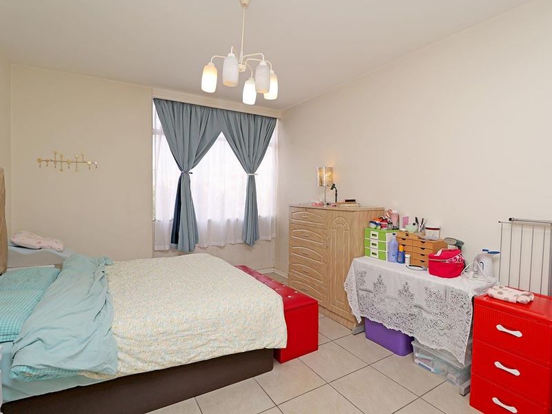 A functional bedroom featuring tiled flooring and a central ceiling light fixture, offering a neutral base for personalization.