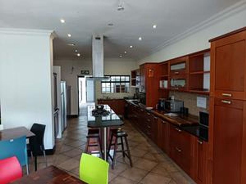 Spacious kitchen featuring extensive wooden cabinetry, granite countertops, a central island with a gas hob, and recessed lighting throughout.