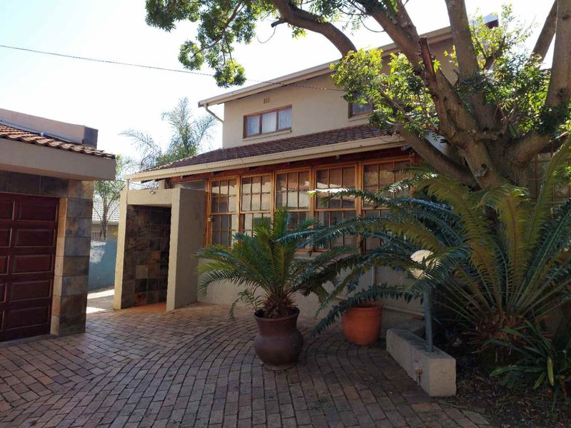 Front exterior view of the apartment featuring a paved driveway, attached garage, and timber-framed windows under a tiled roof.