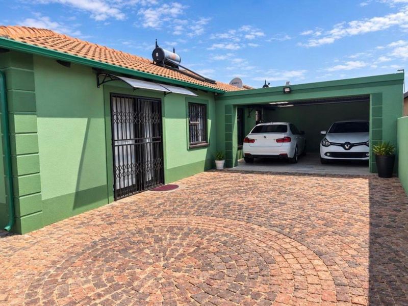 Front exterior view of the house featuring a paved driveway, double garage, and solar water heating system installed on the tiled roof.
