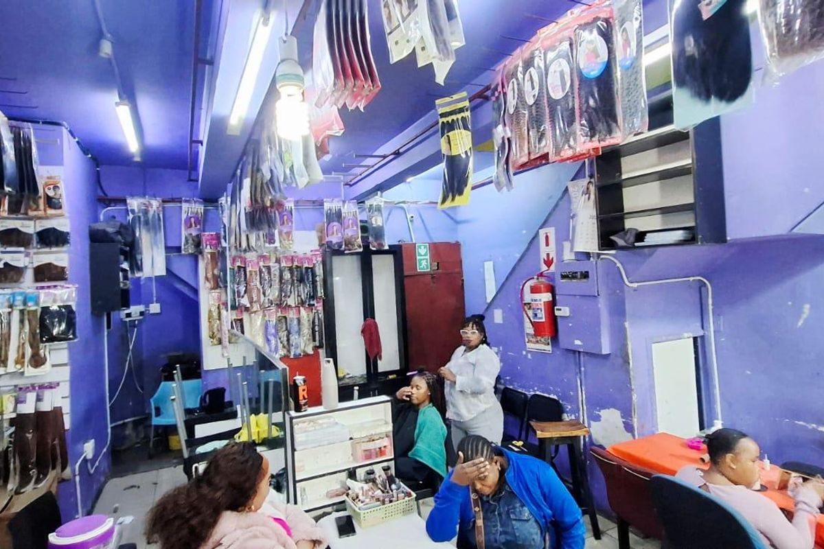 Interior view of a commercial retail space featuring exposed electrical conduits, fluorescent lighting, and wall-mounted fire safety equipment.