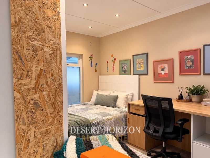 A bedroom featuring a built-in desk and a unique OSB wood panel feature wall, providing a functional and modern aesthetic.