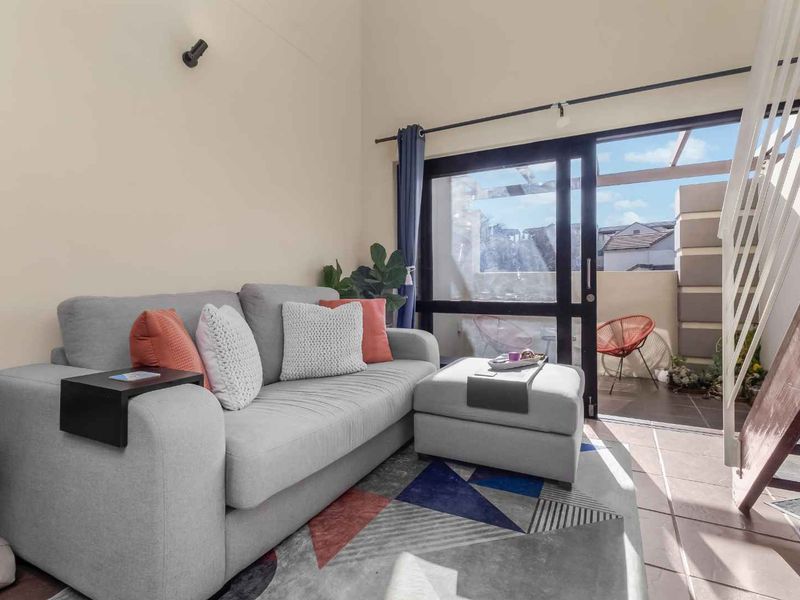 Bright living room featuring high ceilings, tiled flooring, and a sliding glass door providing direct access to an outdoor patio area.