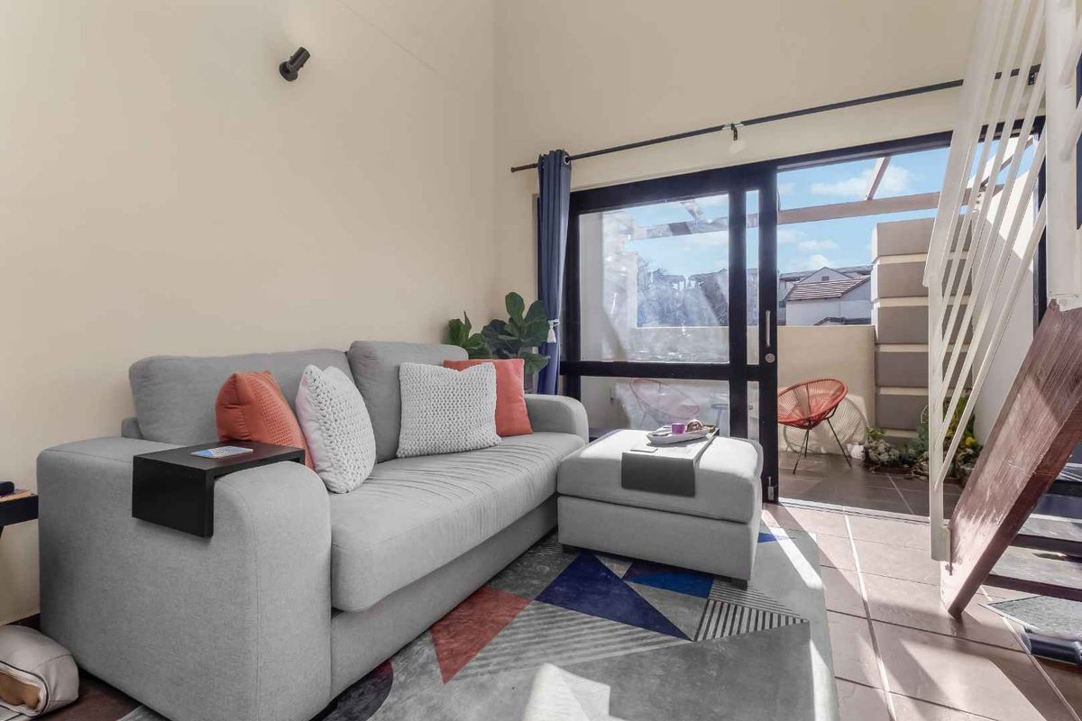 Bright living room featuring high ceilings, tiled flooring, and a sliding glass door providing direct access to an outdoor patio area.