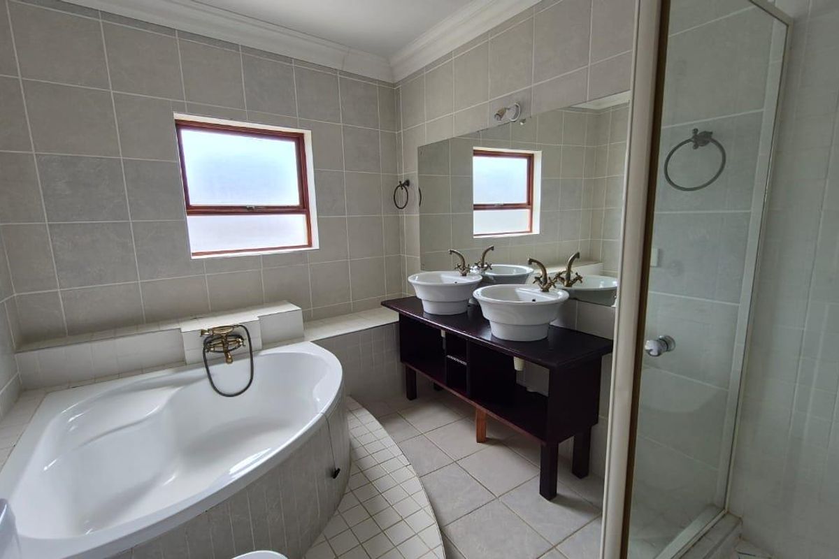 A functional bathroom featuring a corner soaking tub, a separate glass-enclosed shower, and a double vanity with vessel sinks.