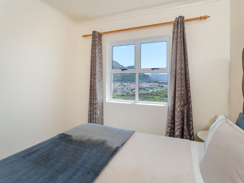 A well-maintained bedroom featuring a window with scenic mountain and neighbourhood views.
