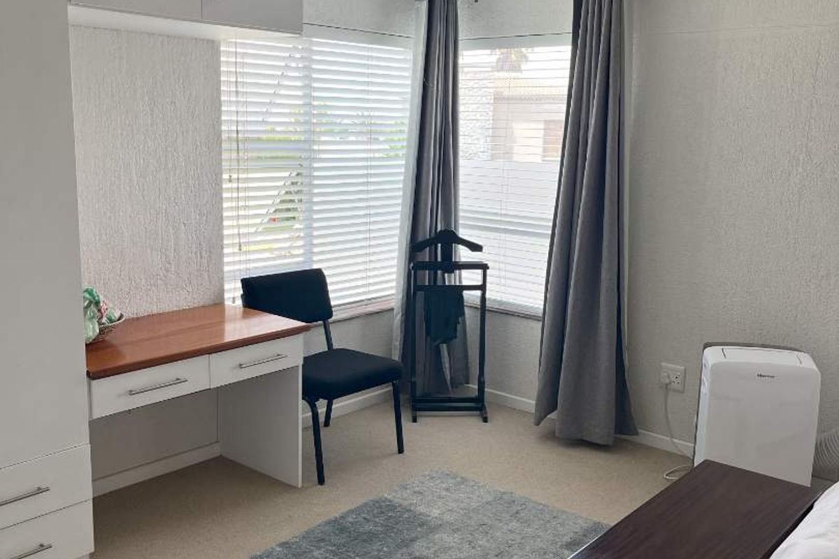 A well-maintained bedroom featuring built-in cabinetry, a desk area, and a ceiling fan, offering a functional and comfortable living space.