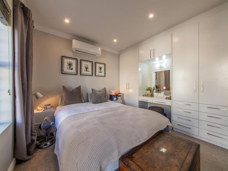 A well-maintained bedroom featuring extensive built-in cabinetry with an integrated vanity, recessed lighting, and a split-system air conditioning unit.