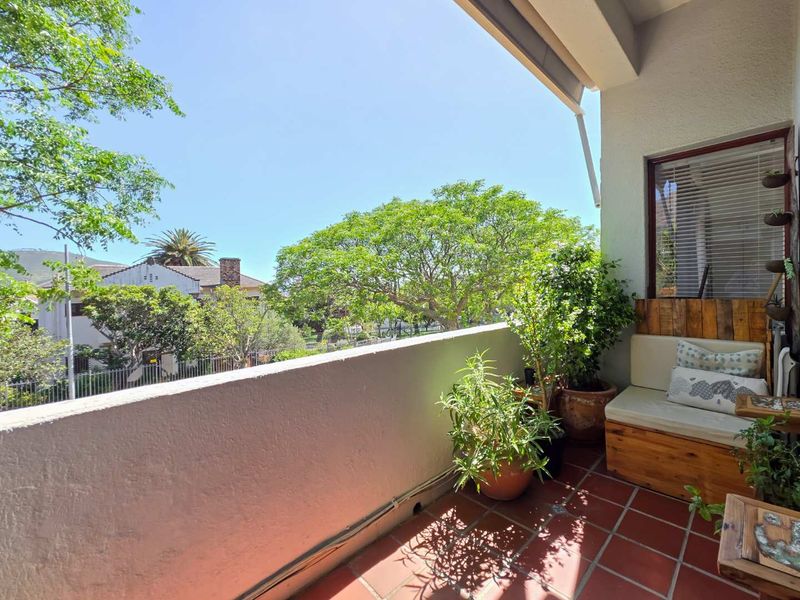 A private balcony featuring terracotta tiled flooring and a solid masonry balustrade, offering a pleasant outdoor space with views of the surrounding greenery.
