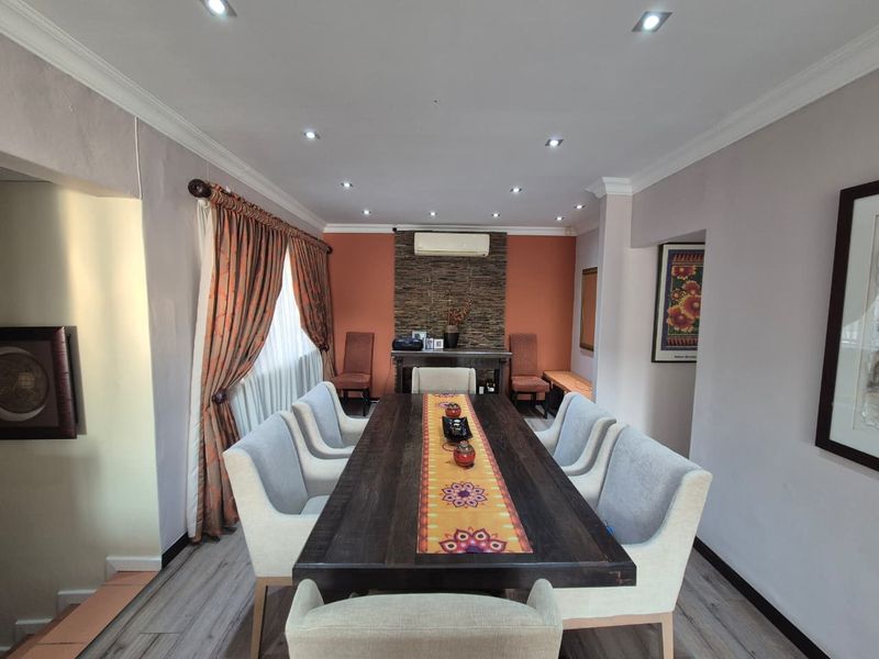 A well-maintained dining room featuring a stone accent wall, recessed downlighting, and modern laminate flooring, providing a comfortable space for formal meals.