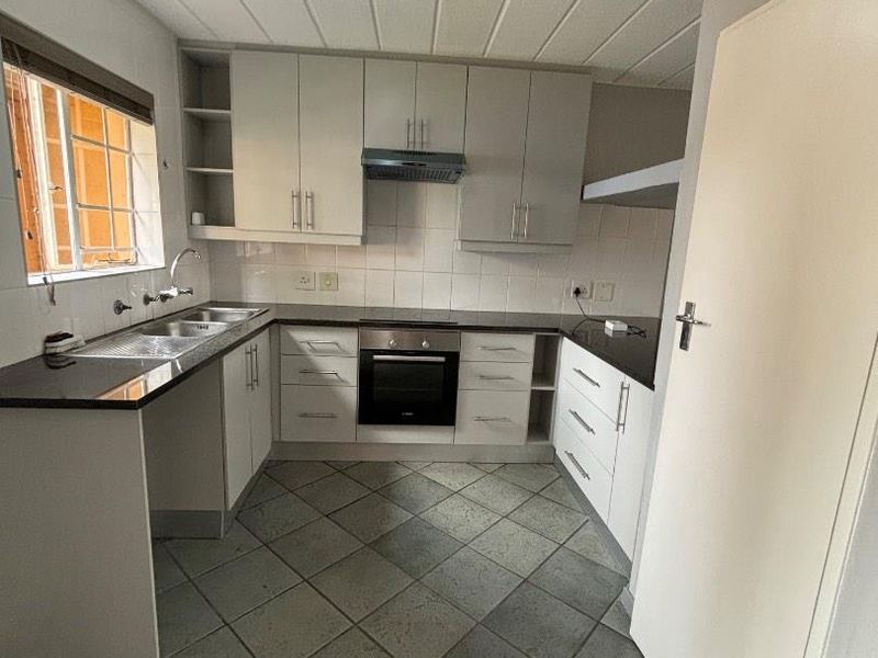A functional kitchen featuring built-in cabinetry, dark laminate countertops, integrated oven and cooktop, and tiled flooring.