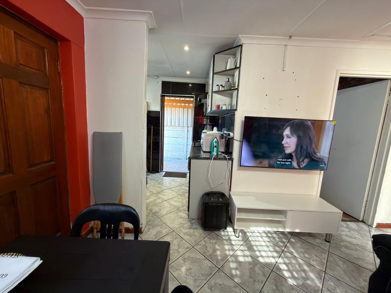 Open plan living area featuring tiled flooring, coved ceilings, and direct access to a rear utility space.